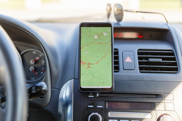 The map on the phone in the background of the dashboard. Black mobile phone with map gps navigation...