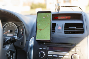 The map on the phone in the background of the dashboard. Black mobile phone with map gps navigation...