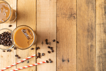 Flat lay. Cold coffee in transparent glasses with ice and straws, on a wooden background, cooling...