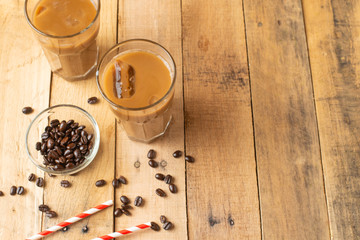 Flat lay. Cold coffee in transparent glasses with ice and straws, on a wooden background, cooling drink, refreshing, summer mood, with copy space