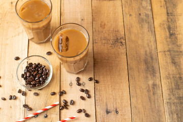 Flat lay. Cold coffee in transparent glasses with ice and straws, on a wooden background, cooling drink, refreshing, summer mood, with copy space