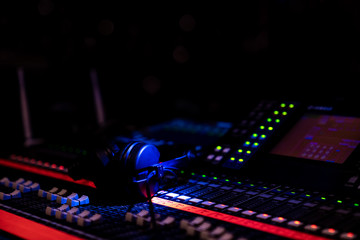 Headphones lying on an advanced mixing console in dim lighting in an event venue