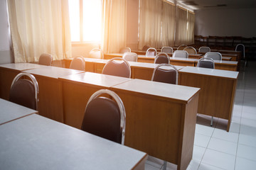 Education concept: Empty college or university classroom with wooden tables and chairs in row without student or teacher in the room. School classroom with window opened, clean and tidy ready for new 