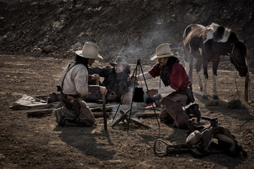 A cowboy's vintage portrait, sitting and holding a gun, with a horse standing beside him.
