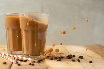 Iced coffee in transparent glasses with ice and straws, on a wooden background, a cooling drink