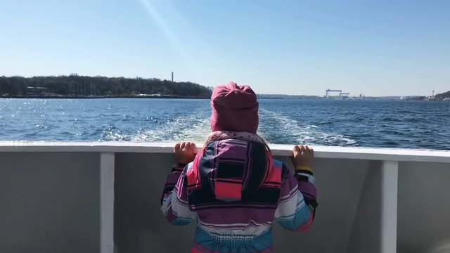 Little girl looking at the blue sea landscape and the beautiful coastline from boat