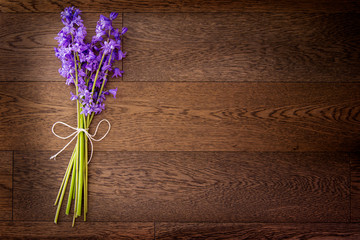Simple bouquet of small purple flowers in a lay flat format; flower stems tied with a bow with twine