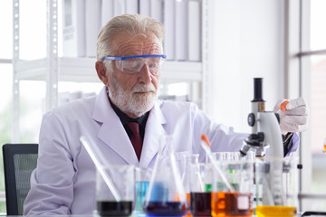 Senior scientist using microscope, Test in the Laboratory.