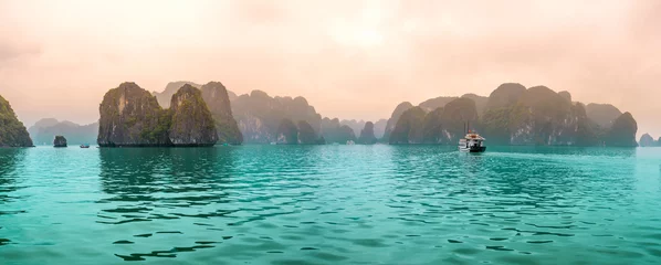 Wunderschönes touristisches Kreuzfahrtschiff, das zwischen Kalksteinfelsen in der Ha Long Bay schwimmt. Dies ist das UNESCO-Weltkulturerbe, es ist ein wunderschönes Naturwunder im Norden Vietnams © huythoai