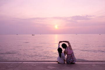 silhouette of woman and daughter on the beach at sunset