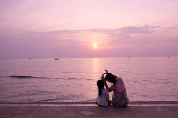 silhouette of woman and daughter on the beach at sunset