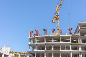 multi-level concrete building under construction with tower crane