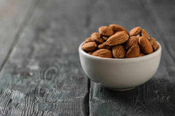 Almonds in a ceramic bowl on a black table.