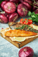 Grilled dorado fish and salmon steak on a wooden board 