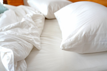 Bedroom and bedding sheets and pillow. Messy bed concept.White themed bed sheets and pillows messed...