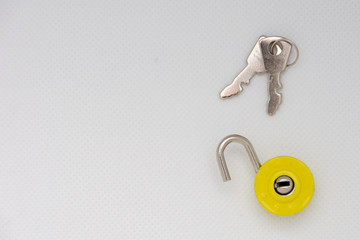 Silver keys and a yellow unlocked padlock on an isolated white background.