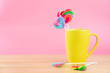 Multicolored lollipops in a container on a pink background