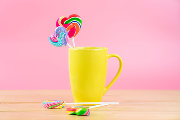 Multicolored lollipops in a container on a pink background