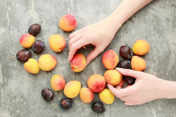 Woman holding peaches and plums, gray stone background