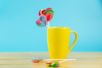 Multicolored lollipops in a container on a blue background with copy space