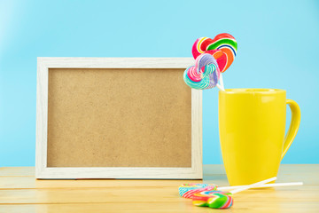 Multicolored lollipops in a container on a blue background with copy space