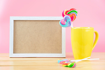 Multicolored lollipops in a container on a pink background with copy space