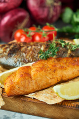Grilled dorado fish and salmon steak on a wooden board 