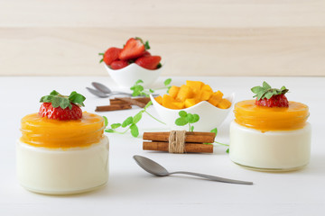 Traditional Italian sweet dessert Panna cotta with mango jelly served in jars and embellished with...