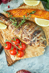Grilled dorado fish and salmon steak on a wooden board 
