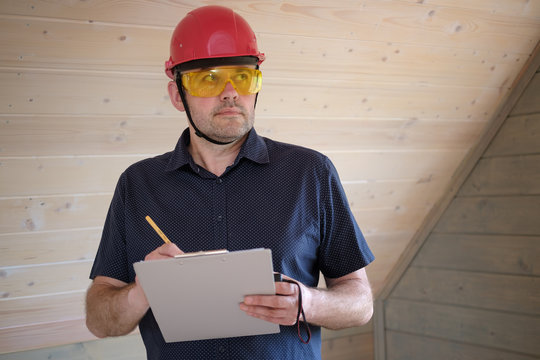 Engineer Builder in a red protective helmet with a tablet in his hands