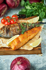 Grilled dorado fish and salmon steak on a wooden board 