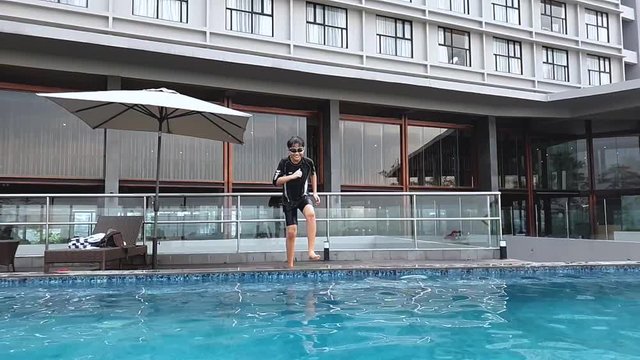 Slow motion of preteen boy jumping on the pool and swimming while enjoying holiday