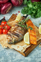 Grilled dorado fish and salmon steak on a wooden board 