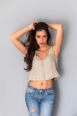 Beautiful sexy young long hair woman in jeans standing in front of wall