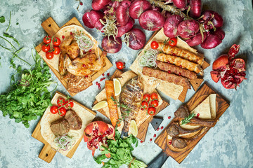 Plates of meat with barbecue and kebab, top view on gray background