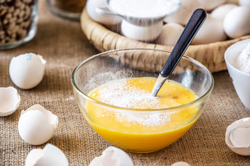 Add flour to a glass bowl with raw eggs.