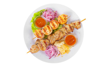 Shish kebab on the grill with pickled onions, cabbage and ketchup, tomato sauce on a plate, isolated on white background, view from above