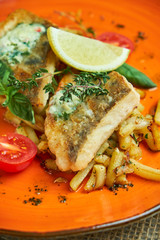 fried fish with vegetables and potatoes on a plate