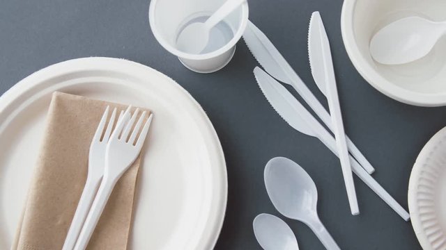 eating, recycling and ecology concept - disposable plastic dishes on grey background