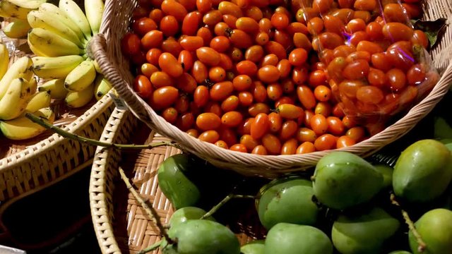 Fruits and vegetables on rustic stall. Assorted fresh ripe fruits and vegetables placed on rustic oriental stall in market. Green mango, tomatoes and yellow banana