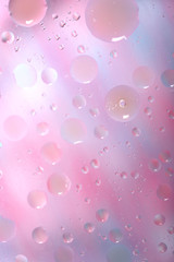 Oil drops in water on a colored background. Surface with pink and light blue circles of different sizes. Background, blur, vertical, nobody, plenty of space for text. Design concept.