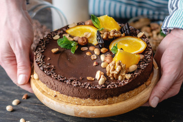 Hands decorated with chocolate cake orange and mint leaves with peanuts and nuts. Healthy raw desserts for vegan food