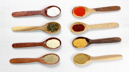 Assortment of spices in wooden spoons, white background
