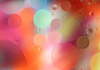Oil drops in water on a colored background. Bright background with pink, orange and yellow circles of different sizes. Blur, horizontal, place for text, multi-color. Concept of design.