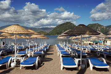 Fototapeta na wymiar Beach. Umbrellas and chaise lounges, bright blue sky and sea. Travel and vacation concept