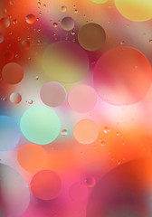 Oil drops in water on a colored background. Bright background with pink, orange and green circles of different sizes. Blur, vertical, place for text, multi-color. Concept of design.
