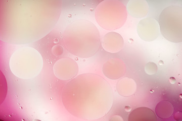 Oil drops in water on a colored background. Surface with pink and white circles of different sizes. Background, blur, horizontal, nobody, plenty of space for text. Design concept.