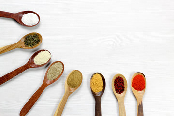 Assortment of spices in wooden spoons, white background