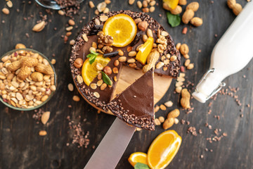 Chocolate cake with orange, cacao, mint leaves, peanuts and nuts. Top view. Concept healthy raw desserts for vegan food