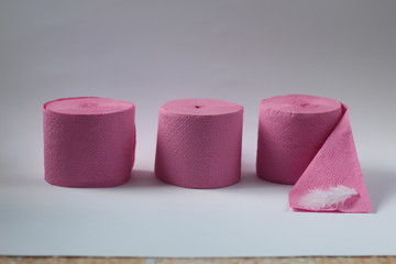 three pink rolls of toilet paper on a white background